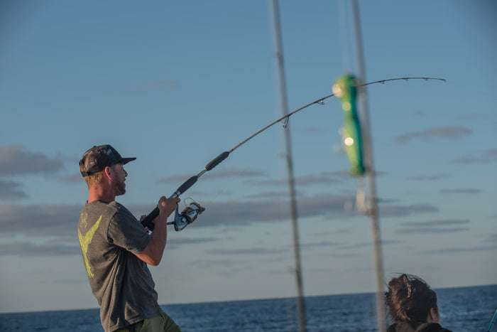 Man fishing on a boat with a clear sky and water background