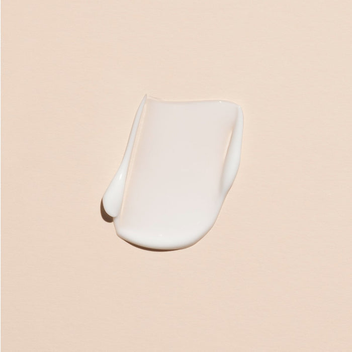 A smear of Manucurist Everyday Orange Blossom Hand Cream - Cosmos Organic sits on a smooth, light beige surface.