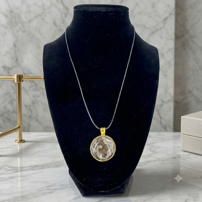 Fort Denaud Beard and Skin round pendant necklace with textured inlay in a gold-tone setting on a black cord