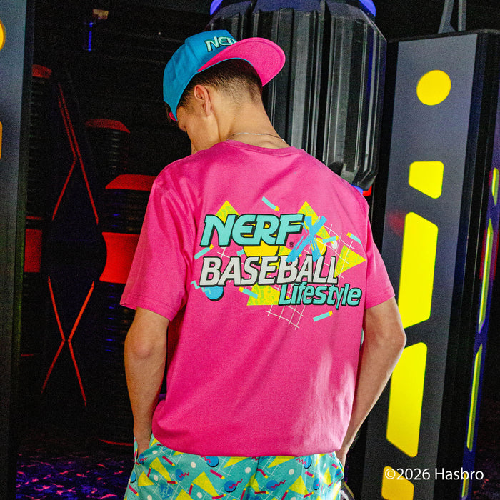 Person wearing a pink 'NERF Baseball Lifestyle' shirt with colorful graphics, standing in front of a vibrant, abstract background.