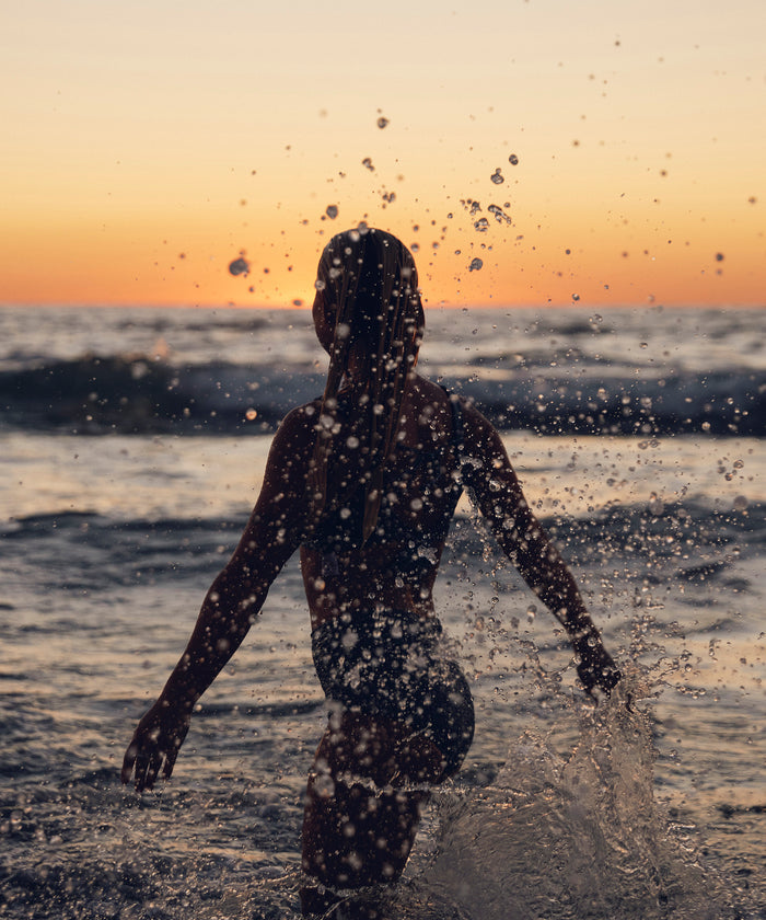 Person playing in the ocean at sunset