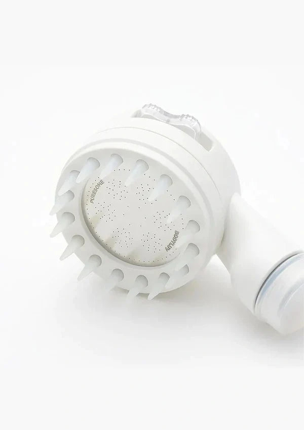 A white electric facial cleansing brush head with multiple silicone bristles and a clear plastic cover, shown on a clean white background.