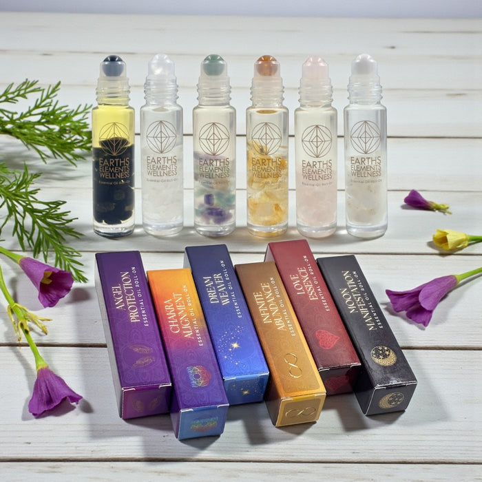 Set of Earth's Elementals roller bottles with their packaging on a wooden surface with flowers.