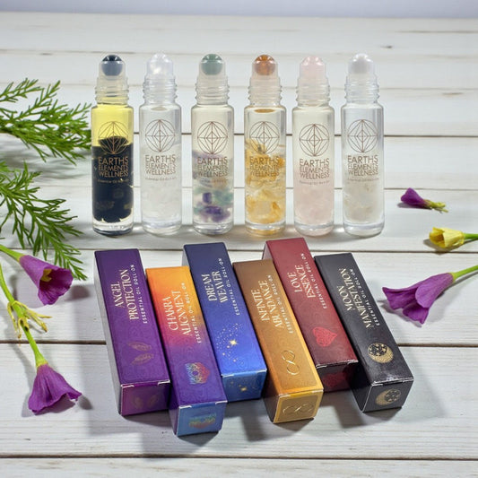 Set of Earth's Elementals roller bottles with their packaging on a wooden surface with flowers.