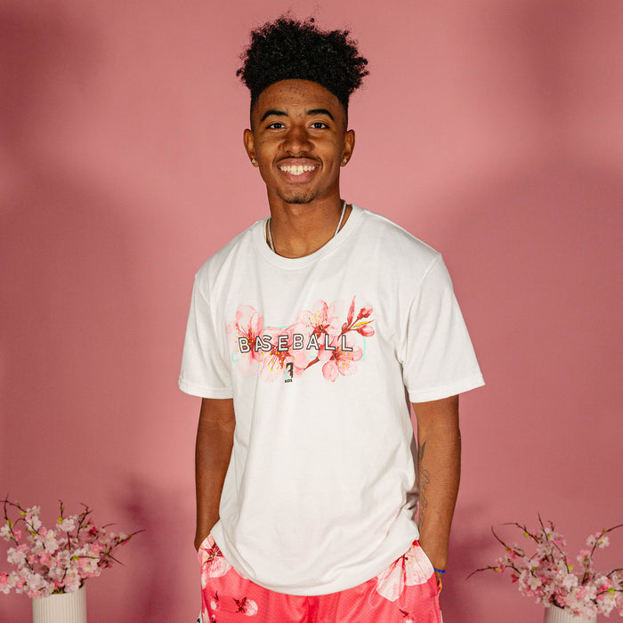 Male model wearing a white BL101 cherry blossom Baseball tee and pink floral shorts against a pink background, front view