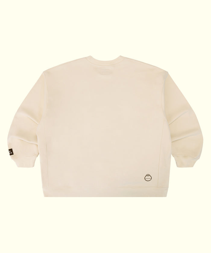 An off-white crewneck sweatshirt shown from the back, featuring a small circular logo on the lower right back and a small black tag on the left sleeve cuff, set against a solid cream background.