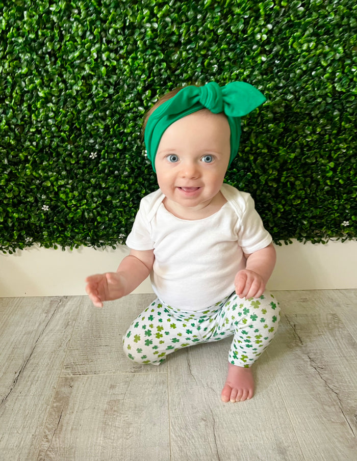 Baby Girl in festive green shamrock print leggings paired with a matching knotted headband, perfect for St. Patrick's Day celebrations or everyday wear. Handmade with soft, stretchy fabric for ultimate comfort and style. Available in sizes preemie to 4T, ideal for your little lucky charm!