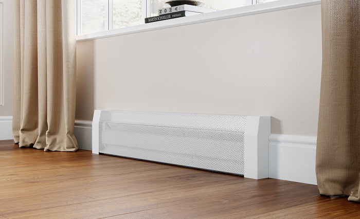 White perforated tall electric baseboard heater cover with end caps, installed on a hardwood floor beneath a window with beige curtains and stacked books on the sill.