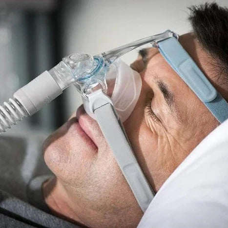 Man wearing a Fisher & Paykel Eson 2 nasal CPAP mask while sleeping on his back.