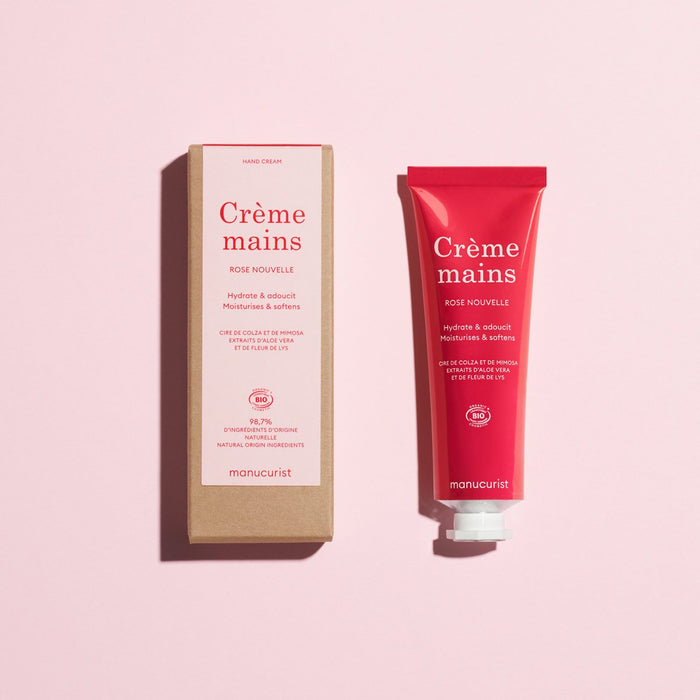 A red tube and a brown box of Everyday Rose Hand Cream - Cosmos Organic by Manucurist are shown on a pink background, both featuring white and pink text.