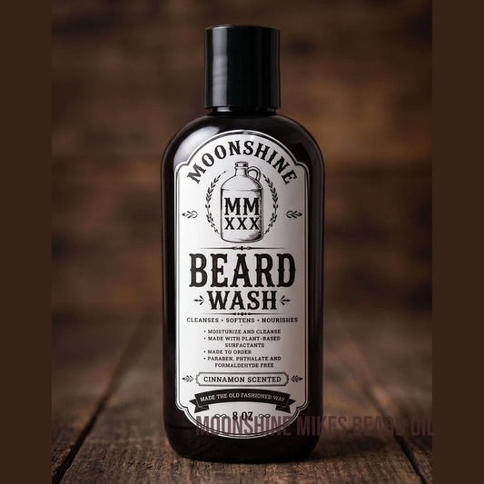 Fort Denaud Beard and Skin Moonshine Mike's cinnamon scented beard wash in a black bottle on a rustic wooden surface.