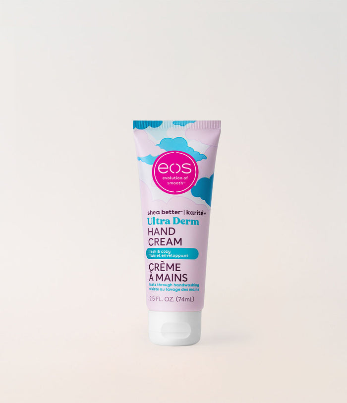 A squeeze tube of EOS Ultra Derm Hand Cream standing upright against a clean, light beige background. The packaging features a pastel lavender body with blue cloud graphics, a pink circular 'eos' logo, and teal and black text.