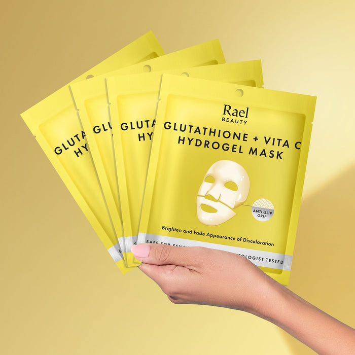 Hand holding Rael Beauty Glutathione + Vita C Hydrogel Mask packages on a yellow background
