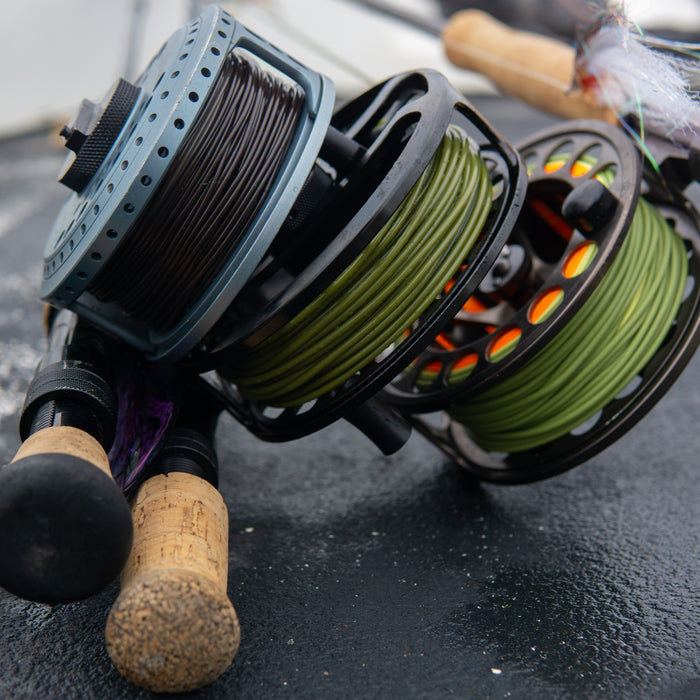 Three fly line reels. One is lined with a brown coil, the other two with olive.