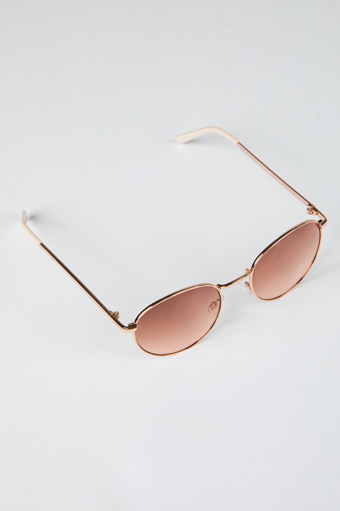 Rose gold sunglasses with pink lenses on a light gray background