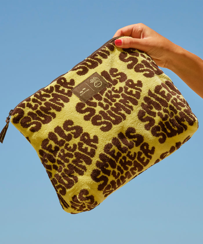 Yellow pouch with brown leopard print text held against a blue sky