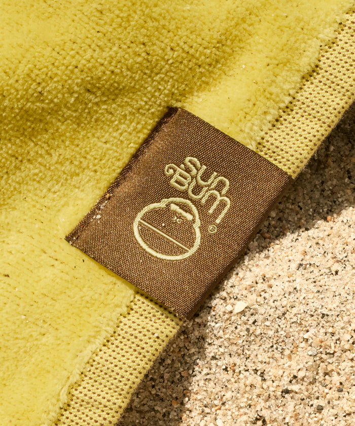 Close-up of a Sun Bum logo on a yellow fabric background