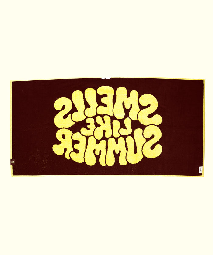 Textile with 'SMELLS LIKE SUMMER' printed in yellow on a brown background