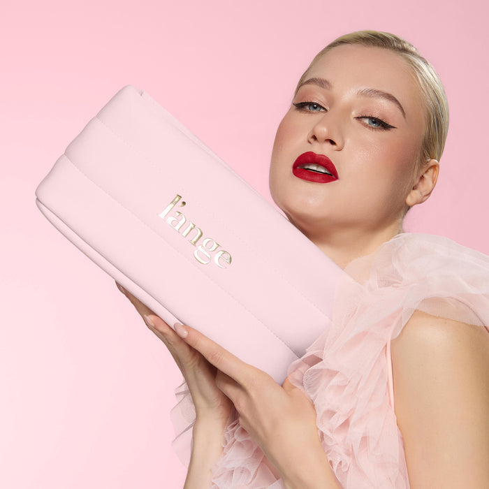 Model holding a blush L’ange bag against pink backdrop