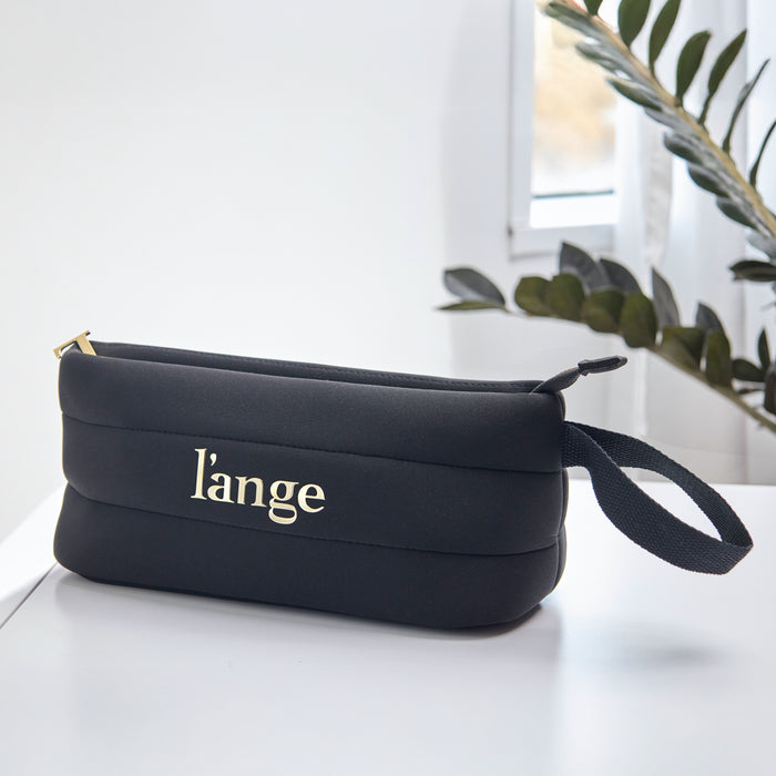 Black L’ange zippered cosmetic bag with gold logo and wrist strap on a white surface.