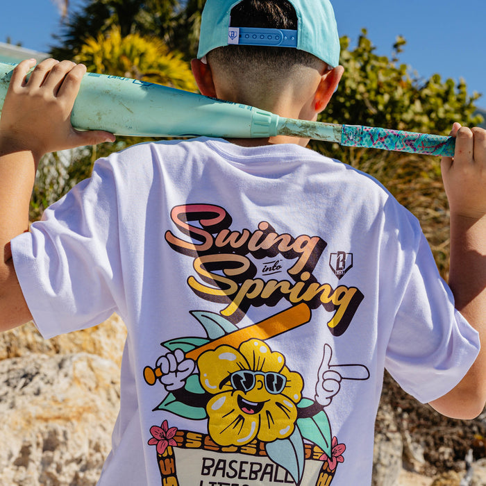 Person wearing a 'Swing into Spring' t-shirt with a baseball bat graphic, holding a colorful bat.