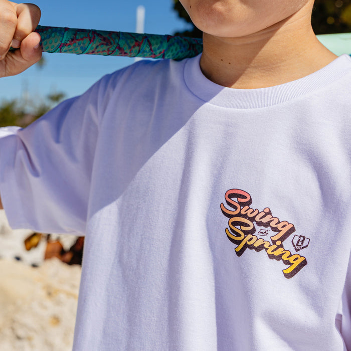 Person wearing a white t-shirt with 'Swing into Spring' text, holding a colorful object.