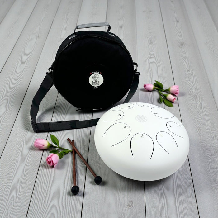 White Steel Tongue Drum - 12" carrying bag, mallets, and flowers on a wooden surface