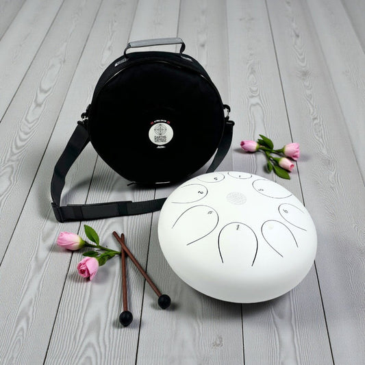 White Steel Tongue Drum - 12" carrying bag, mallets, and flowers on a wooden surface
