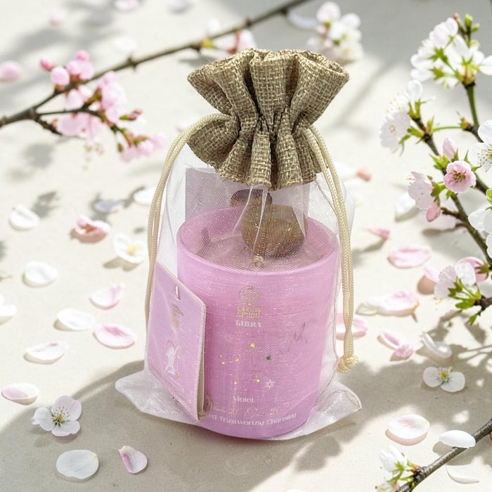 Pink candle in a decorative bag with cherry blossoms in the background