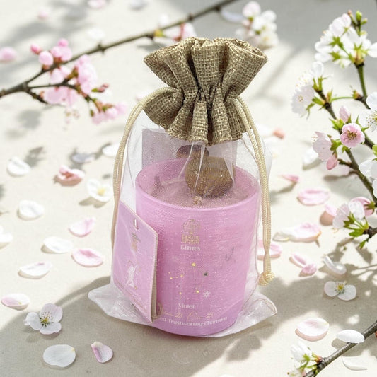 Pink candle in a decorative bag with cherry blossoms in the background