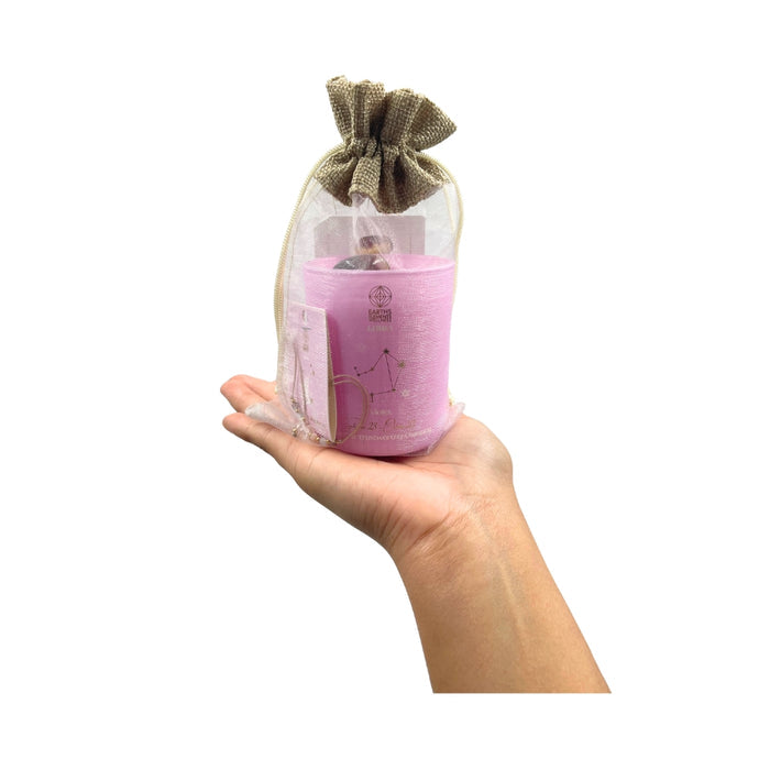 Hand holding a Libra  candle in a drawstring bag on a white background